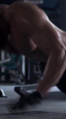 Spor salonunda yerde şınav çeken odaklanmış bir adam. Dayanıklılık, fiziksel egzersiz ve fitness eğitimine adanmışlık. Dikey video.