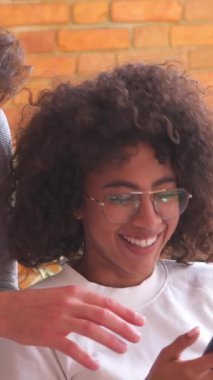 Kız arkadaş ve erkek arkadaş evde birlikte rahatlar, rahatça dinlenirken internet eğlencesi için telefon kullanırlar. Dikey video.