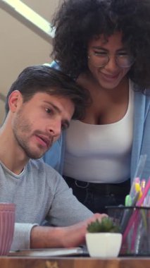 Zaferi ve zaferi kutlayan, ofiste çalışan, coşkulu bir beşlik çakışan bir çift gülümseyen meslektaşız. Dikey video.