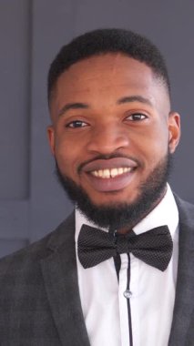 Siyah arka planda takım elbiseli gülümseyen ve neşeli bir Afrikalı Amerikalı 'nın portresi. Zarafet, bireysellik ve olumlu bir tutum. Dikey video.