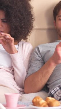 Aile çifti yatak odasındaki online eğlence için cep telefonu kullanıyor. Sabahları birlikte rahat ve soğuk bir yerde vakit geçiriyoruz. Dikey video.