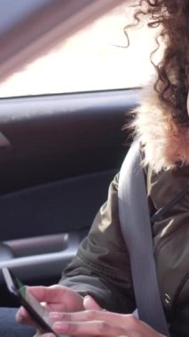 Olumlu kız arkadaş ve erkek arkadaş, açık havada otomobilde oturup, mutlu bir şekilde yol tarifi tartışırken çevrimiçi bir yer aramak için birlikte çalışırlar. Dikey video.