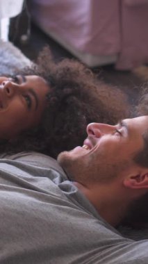 Olumlu eş ve koca yatak odasında dinlenirken, yatakta rahat bir şekilde uzanırken sıcak bir sohbet ederken, huzurlu vakit geçirmenin keyfini çıkarırlar. Dikey video.