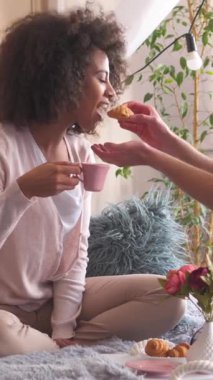 Karı ve koca sabah kahvaltısını yatak odasında yapıyorlar. Yatakta birlikte hoş vakit geçirdikleri için sohbet ve eğlence eğlenceyle harmanlanıyor. Dikey video.