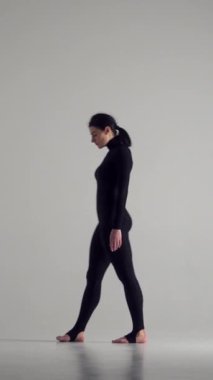 Kadın beyaz arka planda büyüleyici bir dans gösterisi sergiliyor, bireyselliği ve şehveti ifade ediyor. Performans, kadınlığı, sanatçılığı ve şovmenliği yansıtır. Dikey video.