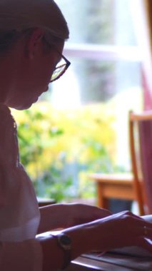 Kütüphanede bir kitapla çalışan özenli bir kütüphaneci, eğitim ve bilgiye odaklanıyor. Kataloglama, bilgi ve profesyonellik. Dikey video.