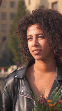 Erkek ve kadın dışarıda buluşurken gülüyor ve sohbet etmekten zevk alıyorlar. Eğlence, rahatlama ve çift arasında neşeli bir bağ. Dikey video.