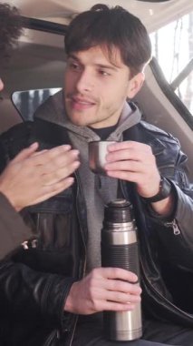 Neşeli erkek ve kadın doğada tatilin tadını çıkarırlar, birlikte çay içerken güzel açık havada dinlenirler. Dikey video.