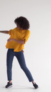 Neşeli ve neşeli Afrikalı Amerikalı kadın, beyaz arka plandaki bir partide müzik eşliğinde dans ediyor. Zevk ve kutlamalardan keyif alıyor. Dikey video.