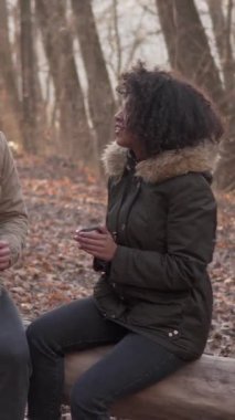 Neşeli kadın ve erkek birlikte dışarıda vakit geçiriyorlar. Huzurlu ormanda yürüyüp eğleniyorlar. Dikey video.