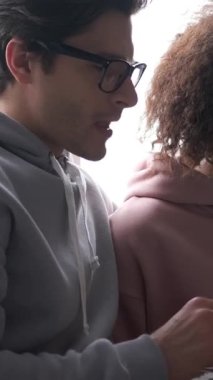 Arkadaş canlısı erkek arkadaş ve kız arkadaş, evde birlikte vakit geçirirken bir tablet bilgisayar kullanarak iletişim kuruyor. Dijital bağlantının rahatlığı. Dikey video.