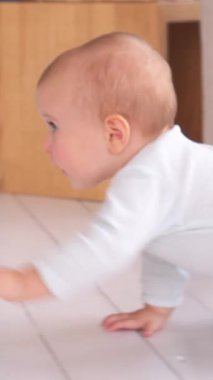 Meraklı bebek evde yerde sürünüyor, etrafı keşfediyor ve keşfediyor. Erken eğitim ve eğlenceli merak. Dikey video.