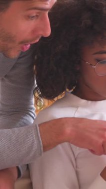 Tatmin olmuş erkek ve kadın evde dinlenirken boş zamanlarında internet aktiviteleri ve akıllı telefondan eğleniyorlar. Dikey video.