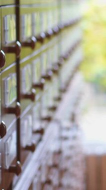 Kütüphaneci çalışıyor, envanter çıkarıyor ve kütüphanede belgeleri alfabetik sıraya göre düzenliyor. Bilgi yönetimi, düzen ve profesyonellik. Dikey video.