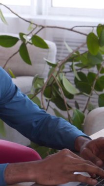 Afrikalı Amerikalı iş adamı evde dizüstü bilgisayarla çalışıyor, sohbet ediyor ve mesajlaşıyor. Meslek, teknoloji ve uzaktan kumanda. Dikey video.