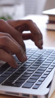 Mutlu Afro-Amerikan serbest çalışanı boş zamanlarında dinleniyor. Ev ofisinde dizüstü bilgisayarla çalışırken sandalyeye yaslanıyor. Rahatlama ve iş hayatı dengesi. Dikey video.