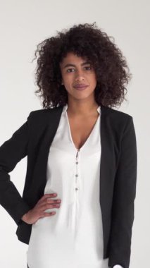 Beyaz bir arka planda resmi giyinmiş mutlu bir Afrikalı Amerikalı kadının portresi. Profesyonellik, bireysellik ve personelle ilgili konsept. Dikey video.