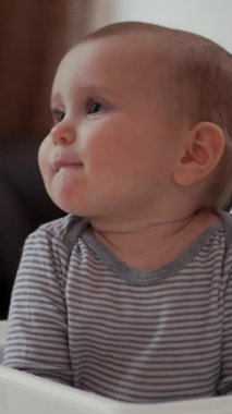 Anne bebeğe kahvaltı hazırlar, evde mutfakta yemek yer, beslenme saatinde bakım ve keyif sağlar. Dikey video.