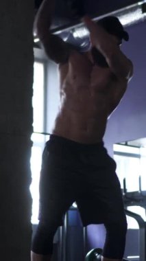 Terli ve kaslı bir adam spor yaparken çekiç egzersizi yapıyor. Güç, kas gücü ve kendini spora adamak. Dikey video.