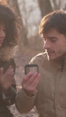 Keyifli orman gezintisi sırasında çay molası veren mutlu karı koca, hafif egzersizle evlilikten keyif almayı birleştiriyor. Dikey video.