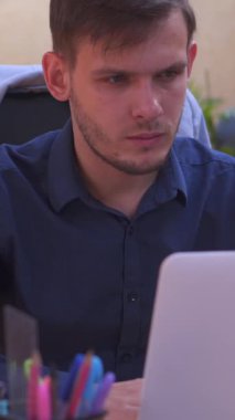 Adam internette bir ofiste dizüstü bilgisayarla çalışıyor, planlama ve muhasebe gibi iş görevlerine odaklanıyor. Üretkenlik, profesyonellik ve modern çalışma ortamları. Dikey video.