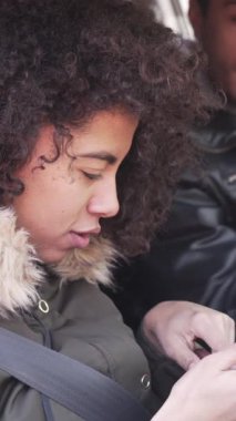 Memnun kadın ve erkek arabada oturup telefondaki online haritayı inceliyor, açık hava ortamının tadını çıkarırken birlikte yol gezisi planlıyorlar. Dikey video.