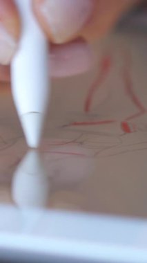 Bir atölyedeki tablet bilgisayara kıyafet çizen bir tasarımcının yakın çekimi. Yaratıcılık, sanat eserleri ve moda tasarımında teknoloji kullanımı. Dikey video.