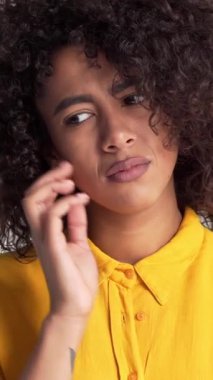 Üzüntülü ve mutsuz bir Afrikalı Amerikalı kadının portresi beyaz bir arka planda, zorluk ve depresyonu ifade ediyor. Dikey video.