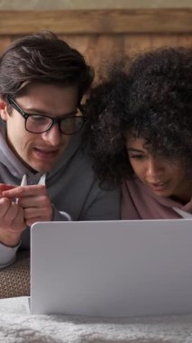 Kız arkadaşı ve erkek arkadaşı evde boş vakitlerinde birlikte eğleniyorlar, birlikte internet aktiviteleri yapıyorlar. Rahat duruş, zevk göstergesidir. Dikey video.