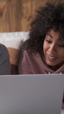 Olumlu kadın ve erkek evde dizüstü bilgisayar kullanarak eğlenceli internet eğlenceleri keşfediyorlar. İfadeler çevrimiçi aktivitelerde paylaşılan zevki yansıtır. Dikey video.