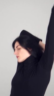 Profesyonel kadın dansçı, beyaz bir arkaplanda, hareket yoluyla şehvet ve sanatını ifade eden çağdaş bir dans sergiliyor. Müzik, performans ve zarafet. Dikey video.