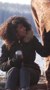 Değer veren bir adam, bir kadını bir battaniyeyle sarıp doğada birlikte dolaşırken, temiz havanın tadını çıkarıyor. Dikey video.