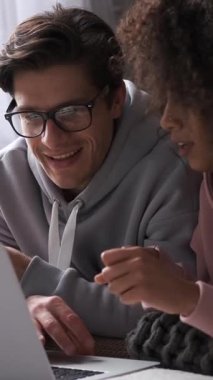 Kadın ve erkek internette dizüstü bilgisayarla geziniyor, evde siber uzay keyfine dalmış halde. Dijital bağlantı. Dikey video.