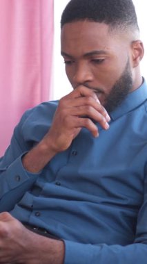 Afrikalı Amerikalı adam evde boş zamanlarında internet eğlencesi ve mesajlaşma için bir tablet kullanıyor. İletişim, rahatlık ve teknoloji. Dikey video.