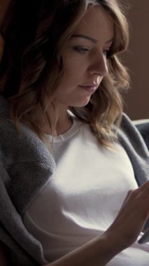 Hamile bir kadın internette sohbet ediyor veya evde bir tablet bilgisayar kullanarak internet eğlencesinden zevk alıyor, eğlence ve teknolojiyi birleştiriyor. Dikey video.