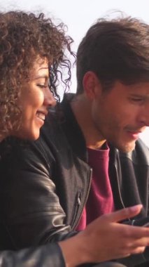 Erkek arkadaşı ve kız arkadaşı açık hava yürüyüşü sırasında cep telefonu kullanarak internette boş vakit geçirmeyi seviyorlar. İletişim, eğlence ve modern bir bağ kurma yöntemi. Dikey video.