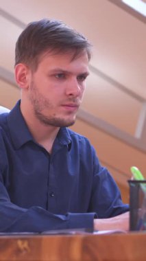 Neşeli ofis çalışanı, ofisteki çerçevedeki aile fotoğrafına bakarak ara veriyor. İş günlerinde sıcaklık, denge ve kişisel anlar. Dikey video.