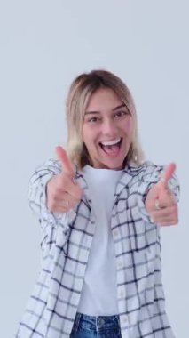 Tatmin olmuş ve mutlu bir kadın beyaz arka planda olumlu duygu ve zaferi ifade eden bir hareket sergiliyor. Dikey video.