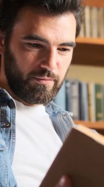 Dost canlısı bir adam evde boş zamanlarını kitap okuyarak geçirir, sakin ve meşgul bir tavırla sakin ve rahat bir ortamın tadını çıkarır. Dikey video.