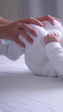 Sağlık bilinci olan anne evde bebek bacaklarına nazikçe masaj yapıyor, bebeklik aktivitelerini ve bağ kurmayı destekliyor, bebeklik konsepti. Dikey video.