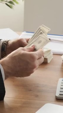 Ofiste nakit sayan, varlıkları, birikimleri ve refahı yöneten, profesyonel bir ortamda özenle finansal varlıkları düzenleyen bir ofis çalışanına yakın plan. Dikey video.