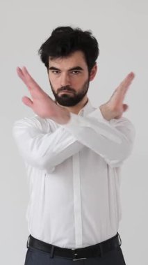 Güçlü bir adam beyaz arka planda çapraz kollu dur işareti gösterir. Güçlü ve kararlı bir tavırla onaylamadığını, protesto ettiğini ve yasakladığını gösterir. Dikey video.