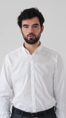 Beyaz arka plandaki bir portredeki adam korku, stres ve endişe verici bir durumun baskısı altında dehşet verici bir ifade iletirken korkmuş ve şok olmuş görünüyor. Dikey video.