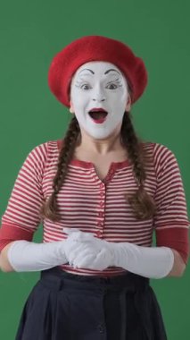 Yeşil arka planda hayret verici bir şekilde alkışlayan ve haykıran olumlu pandomimci, iyi habere coşkulu jestlerle tepki veriyor. Dikey video.