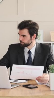 Ofiste evrak işleri ve beyannameleri düzenleyen, muhasebe ve bütçeye odaklanan, yapılandırılmış profesyonel çevrede düzeni sağlayan organize bir çalışan. Dikey video.