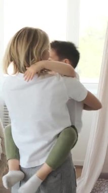 Anne ve oğul evde birlikte oynayıp eğleniyorlar, sevgi gösteriyorlar, destekleyici bir aile ortamında neşeli ve sevgi dolu anılar yaratıyorlar. Dikey video.