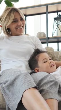 Anne ve oğul evde sohbet ediyor ve birlikte dinleniyorlar, sıcak bir ev ortamında boş zamanlarında iletişim ve şefkat geliştiriyorlar. Dikey video.