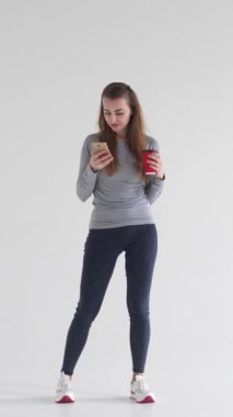 Çevrimiçi boş zamanlarında, sakin ve neşeli bir tavırla eğlence ve iletişim kuran, telefonuyla rahatlayan olumlu bir kadın. Dikey video.