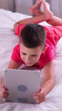 Pozitif öğrenci evde online eğlence ve video oyunları için tablet bilgisayar kullanıyor. Teknoloji aygıtı ve keyfi ile yurt içi boş zamanlarında siber uzay eğlencesi. Dikey video.