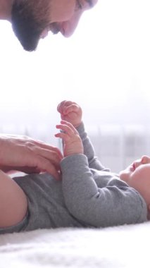 Mutlu orta yaşlı bir baba evde oyun oynarken ve bebek gıdıklarken. Babalık ve mutluluk kavramı. Dikey video.